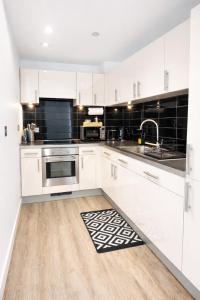 a white kitchen with white cabinets and a sink at Apartment in MediaCity in Manchester