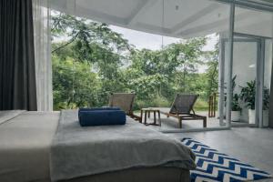a bedroom with a bed and chairs and a large window at Lighthouse Bingin - 360 view in Uluwatu