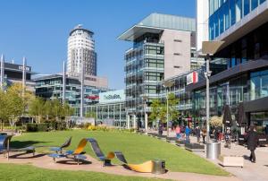 a park with chairs and buildings in a city at Apartment in MediaCity in Manchester