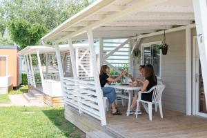 two women sitting at a table under a pergola at Campeggio Paradiso in Sottomarina