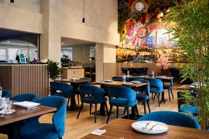 a restaurant with wooden tables and blue chairs at Rotterdam Teleport Hotel in Rotterdam
