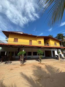 a yellow building with two trees in front of it at Pousada Raios do Sol in Amontada