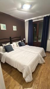 a bedroom with a large white bed with blue curtains at Casa rural marga in Tardienta