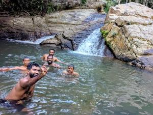 a group of men in the water near a waterfall at Wellassa Hillside Villa in Kendagolla +1 photo