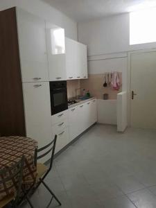 a kitchen with white cabinets and a table and a table and chairs at terra e mare in Collemeto