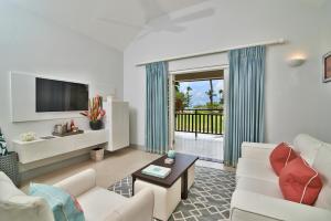 a living room with a couch and a tv at Calabash Hotel in Saint Georgeʼs