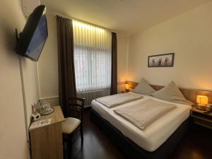 a hotel room with a bed and a flat screen tv at Hotel Hüttl in Worms