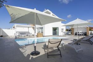 a patio with chairs and an umbrella and a pool at Villa Nidea in Ragusa