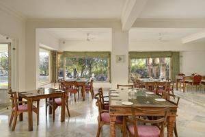 a dining room with tables and chairs and windows at Fateh Safari Resort by Fateh Collection in Kumbhalgarh