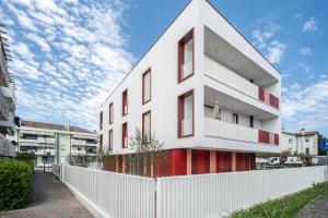 a white building with red windows and a white fence at A&G Blue flat in Cavallino-Treporti