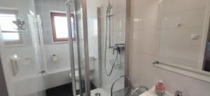 a white bathroom with a shower and a sink at Ferienwohnung Liebau in Bayerisch Eisenstein +19 photos