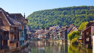 a river in a town with houses and a person in a boat at Le Refuge des Loups Blancs 12 pers in Ouhans +17 photos