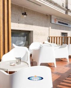 a group of white chairs and tables on a patio at Albergue As Pozas Termais in Caldas de Reis