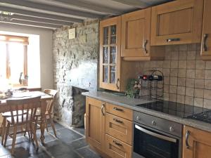 a kitchen with wooden cabinets and a table and a dining room at 3 Bed in Blaenau Ffestiniog oc-wah538 in Trawsfynydd