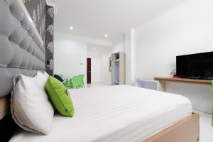 a bedroom with a large white bed with green pillows at Urbanview Hotel Niraz Banjarmasin by RedDoorz in Sungai Lutus