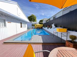 a swimming pool with an umbrella on a wooden deck at Kowhai Motel Rotorua in Rotorua
