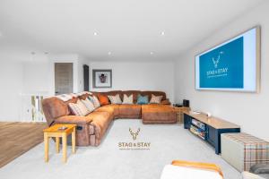 a living room with a brown leather couch at Stag & Stay- Waterlillie - Contractor friendly, Fast WiFi in Port Glasgow