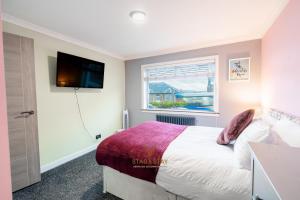 a bedroom with a bed and a tv on the wall at Stag & Stay- Waterlillie - Contractor friendly, Fast WiFi in Port Glasgow