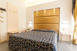 a bedroom with a large bed with a large headboard at Hotel Ambassador in Rimini