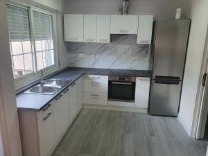 a kitchen with white cabinets and a stainless steel refrigerator at La calma de Aisheric in Nigrán +5 photos