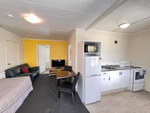 a hotel room with a bed and a kitchen and a room at Kowhai Motel Rotorua in Rotorua