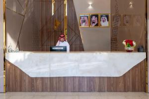 a man sitting at a counter with a laptop at بيست ليفل للشقق المخدومة in Al Khobar