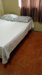 a bed in a room with a wooden floor at Pausada Regis in Lavras