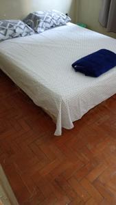 a white bed with a blue pillow on a wooden floor at Pausada Regis in Lavras