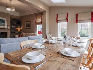 a dining room with a wooden table with plates and wine glasses at Holly Lodge in Aldeburgh