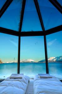two beds in a room with a view of the water at Lyngen Aurora Resort in Koppangen