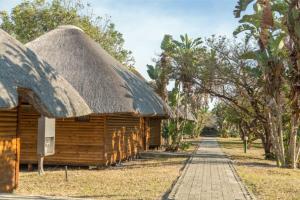 a wooden hut with a thatched roof and a road at Sodwana Bay Lodge Dive & Fishing Resort in Sodwana Bay