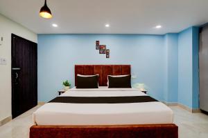 a bedroom with a large bed with a blue wall at Hotel O Khusi Tranquil Domicile in Bhubaneshwar
