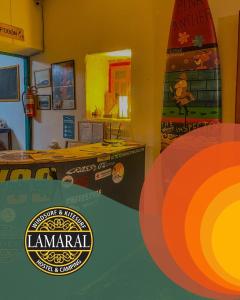 a room with a surfboard and a room with a table at Rancho Lamaral Hostel & Camping in Rodeo
