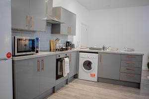 a kitchen with white cabinets and a washer and dryer at Flat 2 Aylesbury Street in Bletchley