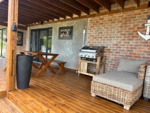 a patio with a grill and a chair and a table at Sea La Mer Villa in Wilderness