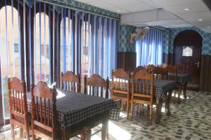 a dining room with tables and chairs and blue curtains at Siachen Hotel in Kargil