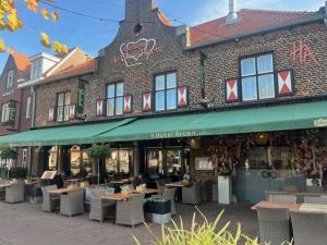 ein Restaurant mit Tischen und Stühlen vor einem Gebäude in der Unterkunft Hotel Arcen in Arcen