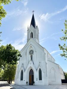 a white church with a steeple and a cross at Betania in Carhué
