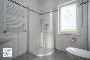 a white bathroom with a shower and a sink at Wald und See Dargun 16b in Dargun
