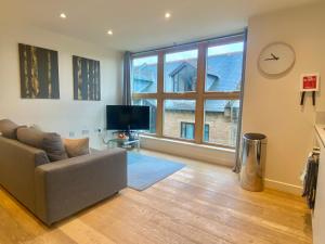 a living room with a couch and a large window at Your Space Apartments - Cambridge Place in Cambridge