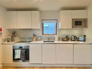 a kitchen with white cabinets and a sink and a window at Your Space Apartments - Cambridge Place in Cambridge