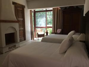 een slaapkamer met 2 bedden, een open haard en een raam bij Hotel Casa del Angel in Tepoztlán