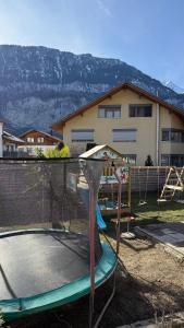 a playground with a trampoline in front of a house at Meiringen Retreat - Sauna, Terrace & Pinball in Meiringen