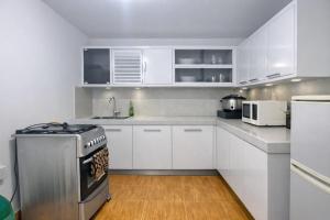 a kitchen with white cabinets and a stove at Kandy Royal Resort in Kandy