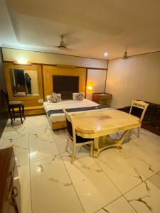 a hotel room with a bed and a table and chairs at Hotel Rahul Deluxe in Nagpur