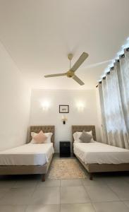 two beds in a room with a ceiling fan at Villa Mistora in Kandy