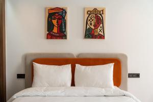 two paintings above a bed with three pillows at Résidence Happy Living in Casablanca