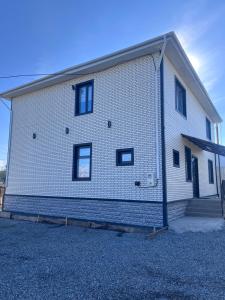 a white brick building with black windows on it at MARAL GuestHouse in Karakol