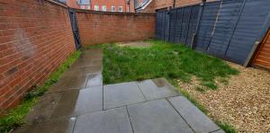 a backyard with a brick fence and a grassy yard at Vantage Stays in Gloucestershire