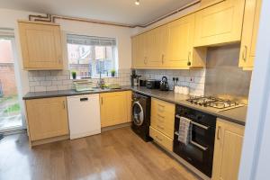 a kitchen with wooden cabinets and a washer and dryer at Vantage Stays in Gloucestershire